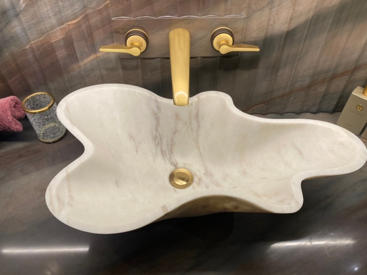 Marble basin with brushed brass wall-mounted mixer tap, installed in a London bathroom