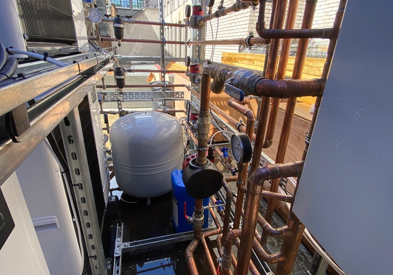 Rooftop plant installation with copper pipework, expansion vessel and air source heat pump